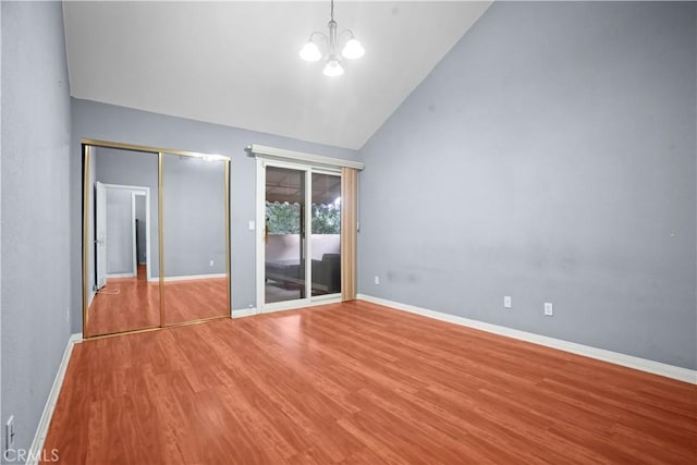 unfurnished bedroom with high vaulted ceiling, an inviting chandelier, access to outside, light hardwood / wood-style flooring, and a closet