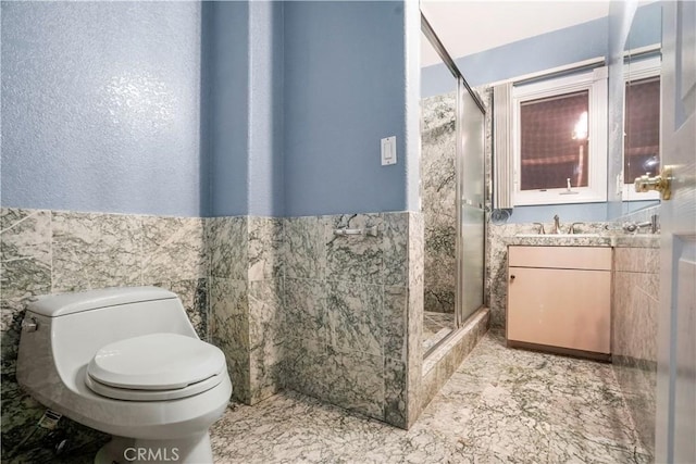 bathroom featuring vanity, toilet, a shower with door, and tile walls