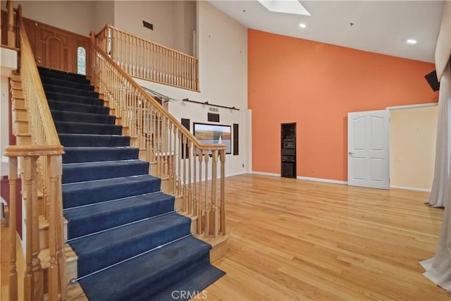 stairway featuring wood-type flooring, a skylight, and high vaulted ceiling