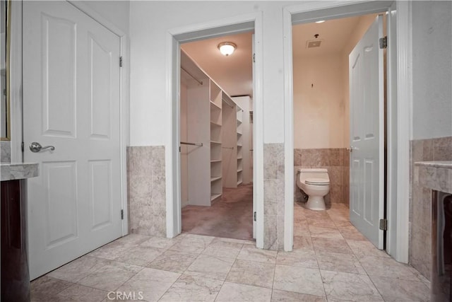 bathroom featuring a fireplace, tile walls, and toilet