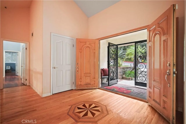 foyer entrance with light hardwood / wood-style flooring and high vaulted ceiling