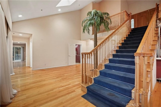 stairway featuring hardwood / wood-style floors, a skylight, and high vaulted ceiling