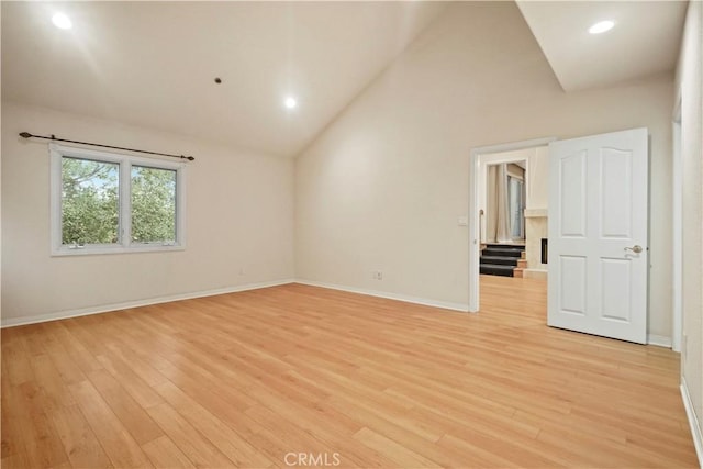 spare room with high vaulted ceiling and light hardwood / wood-style flooring