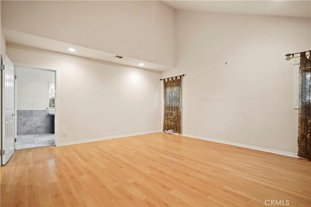 empty room featuring light hardwood / wood-style flooring and high vaulted ceiling