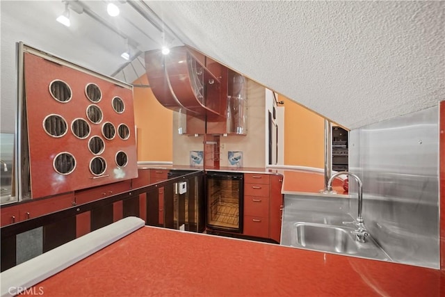 kitchen with a textured ceiling, sink, wine cooler, and track lighting