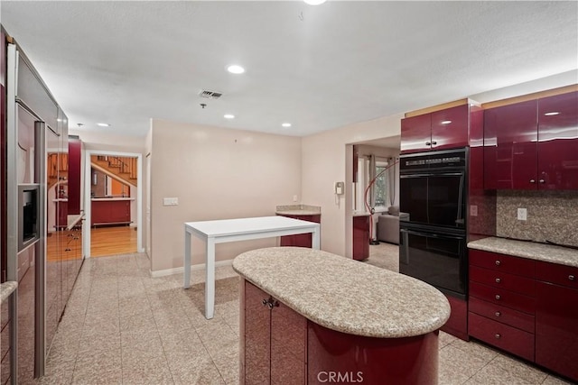 kitchen with double oven, a breakfast bar, decorative backsplash, and a center island