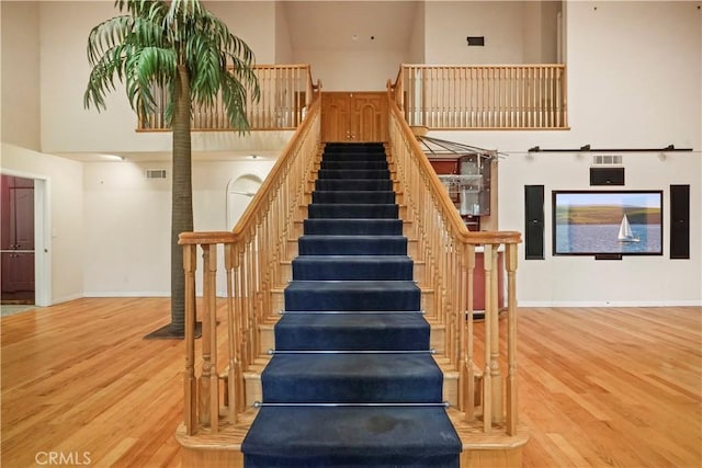 stairway with wood-type flooring and a high ceiling