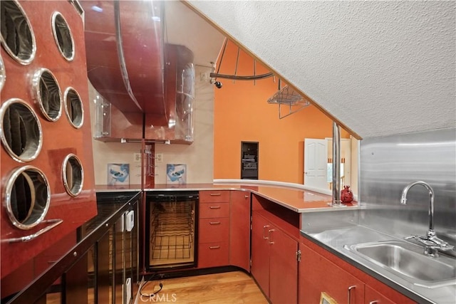 kitchen featuring a textured ceiling, sink, wine cooler, and light hardwood / wood-style flooring