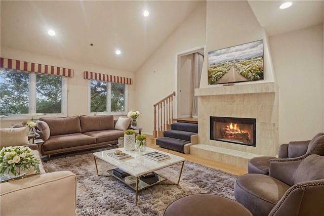 living room featuring hardwood / wood-style flooring, high vaulted ceiling, and a premium fireplace