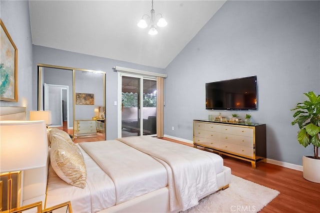 bedroom with hardwood / wood-style flooring, access to exterior, high vaulted ceiling, and an inviting chandelier