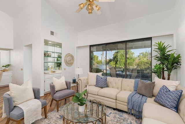 living room featuring ceiling fan, high vaulted ceiling, and light wood-type flooring