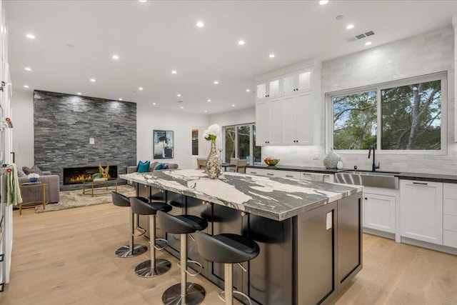 kitchen with a breakfast bar area, sink, a kitchen island, and dark stone counters