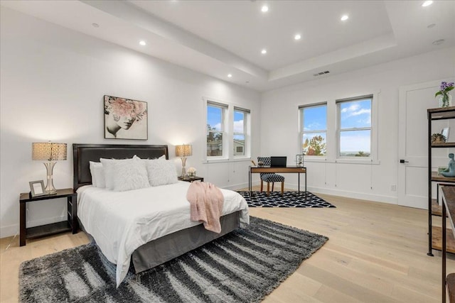 bedroom with a tray ceiling and light hardwood / wood-style flooring