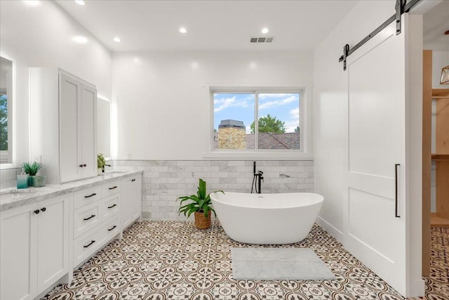 bathroom featuring tile patterned flooring, vanity, a tub to relax in, and tile walls