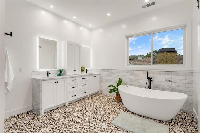 bathroom with vanity, tile patterned floors, tile walls, and a tub