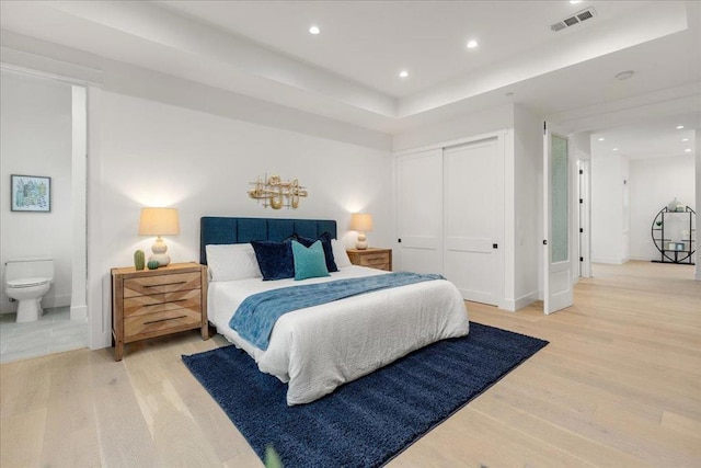 bedroom with hardwood / wood-style floors, connected bathroom, and a closet