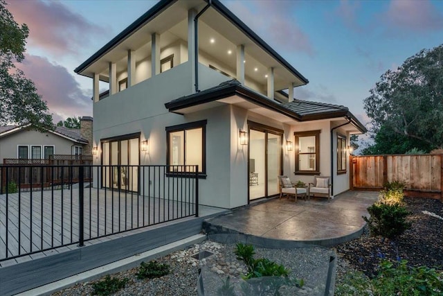 back house at dusk with an outdoor living space and a patio area