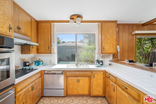 kitchen with tile countertops, stainless steel appliances, tasteful backsplash, and sink