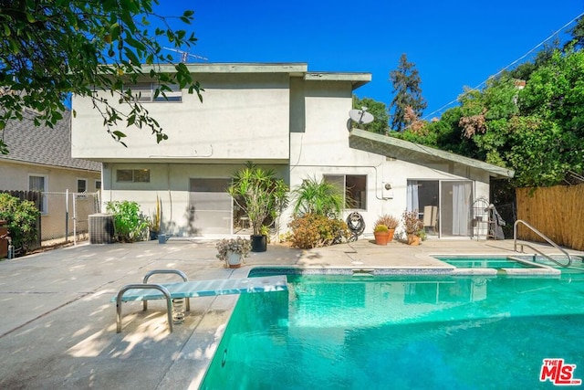 back of house with a patio area, a swimming pool with hot tub, and cooling unit