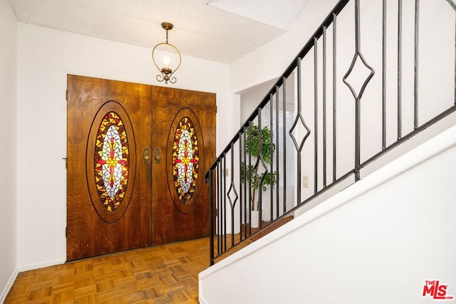 foyer entrance featuring a textured ceiling and parquet floors