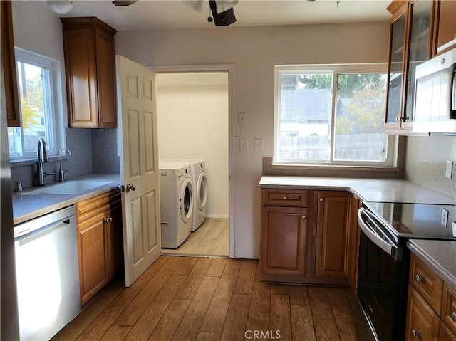 kitchen with washer and dryer, a healthy amount of sunlight, sink, and appliances with stainless steel finishes