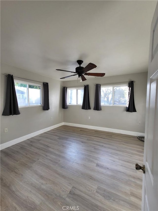 spare room with plenty of natural light, ceiling fan, and light hardwood / wood-style flooring