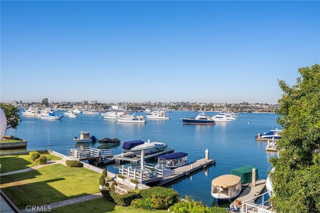 view of dock with a lawn and a water view