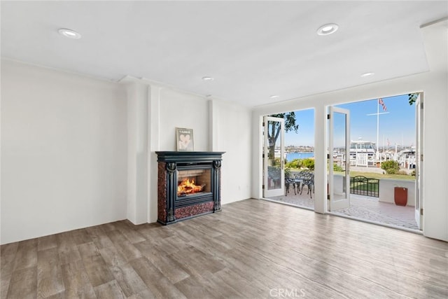 unfurnished living room with french doors, a water view, and light hardwood / wood-style floors