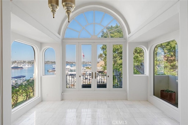 sunroom with a wealth of natural light, french doors, a water view, and vaulted ceiling