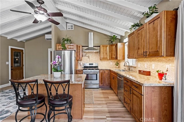 kitchen with sink, a kitchen breakfast bar, stainless steel appliances, a center island, and wall chimney exhaust hood