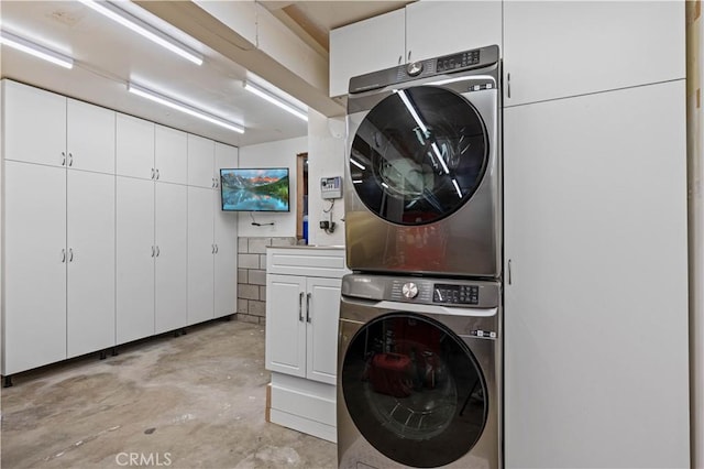 laundry area featuring cabinets and stacked washer and clothes dryer