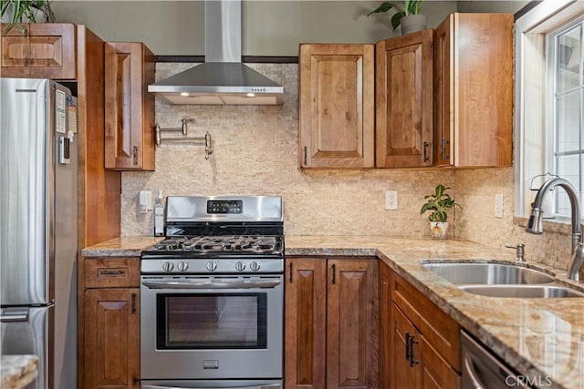 kitchen featuring sink, backsplash, stainless steel appliances, light stone countertops, and wall chimney range hood