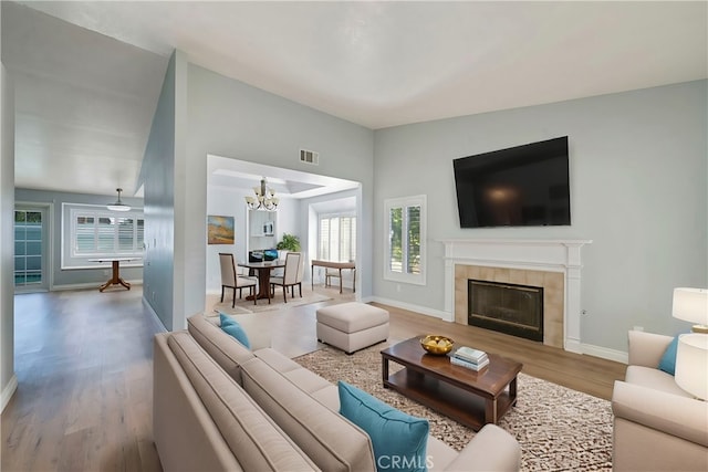 living room featuring wood-type flooring, a notable chandelier, and a fireplace