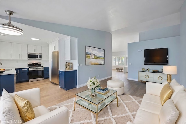 living room featuring lofted ceiling, light hardwood / wood-style floors, and sink