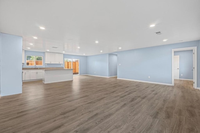 unfurnished living room featuring wood-type flooring and sink