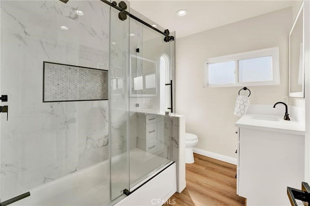 full bathroom with shower / bath combination with glass door, hardwood / wood-style floors, vanity, and toilet