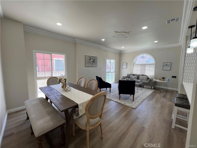 dining room with wood-type flooring and crown molding