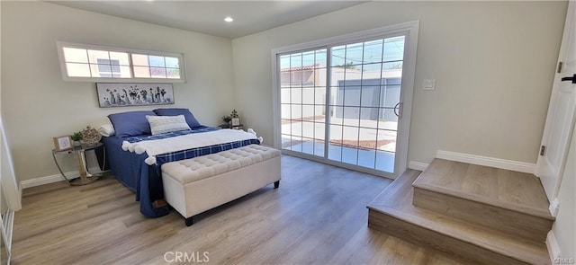 bedroom with light wood-type flooring, access to outside, and multiple windows