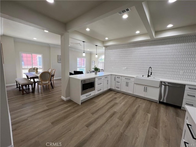 kitchen with pendant lighting, white cabinets, sink, decorative backsplash, and appliances with stainless steel finishes