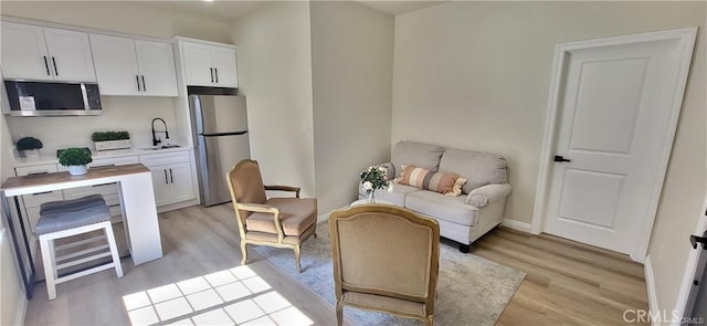 living area with sink and light wood-type flooring