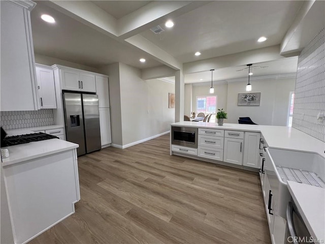 kitchen with white cabinetry, stainless steel appliances, hanging light fixtures, and light hardwood / wood-style flooring