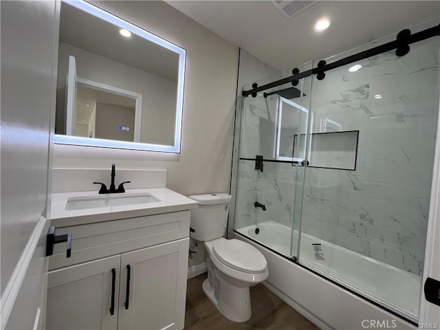 full bathroom with combined bath / shower with glass door, hardwood / wood-style floors, vanity, and toilet