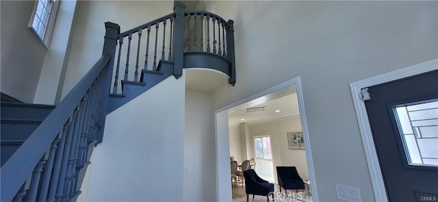 stairway with ornamental molding and a high ceiling