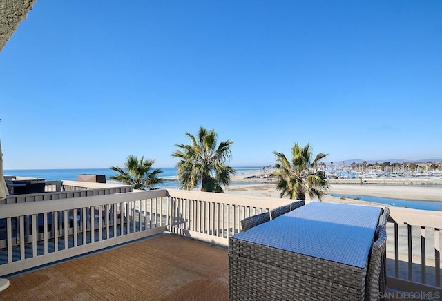 view of patio with a view of the beach, a water view, and a balcony