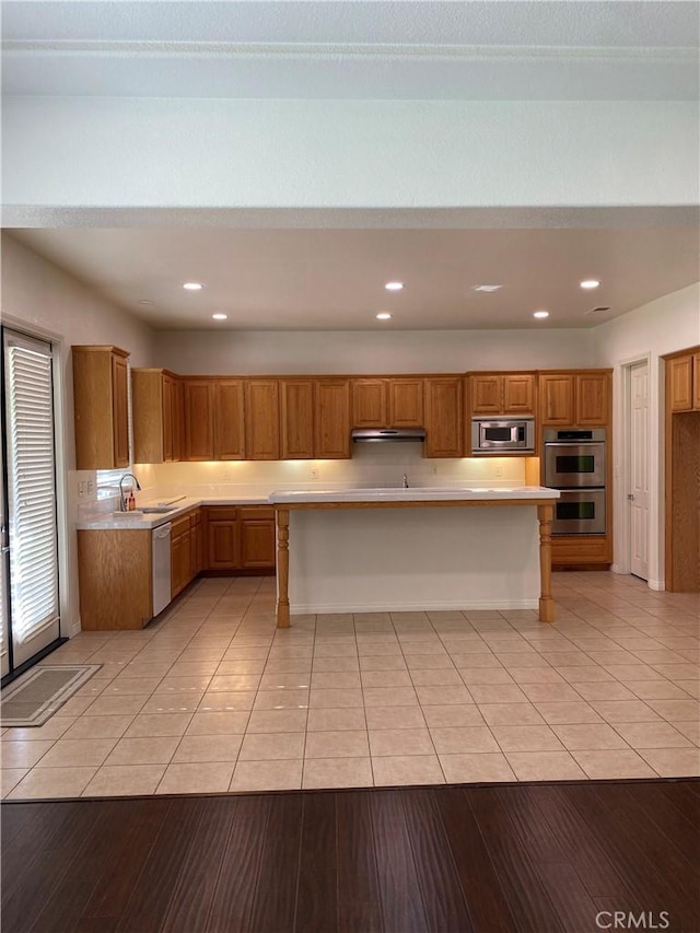 kitchen featuring a kitchen breakfast bar, light tile patterned floors, stainless steel appliances, and a kitchen island