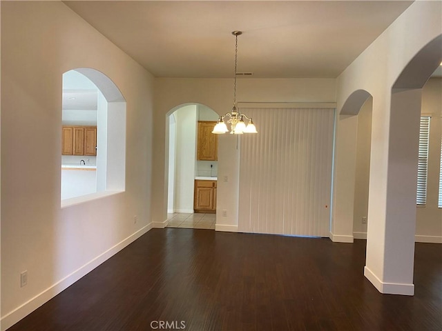 unfurnished dining area with a chandelier and wood-type flooring