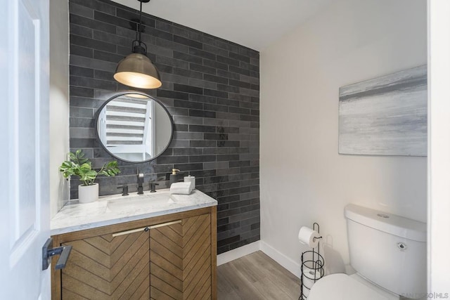 bathroom featuring toilet, vanity, wood-type flooring, and backsplash