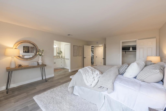 bedroom with a closet, a walk in closet, wood-type flooring, and ensuite bath