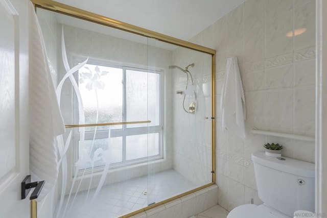 bathroom with a shower with shower door, tile walls, and toilet