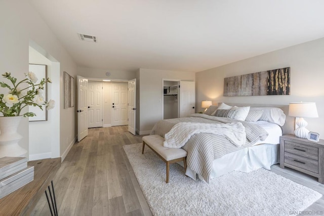 bedroom featuring a spacious closet, light hardwood / wood-style flooring, and a closet